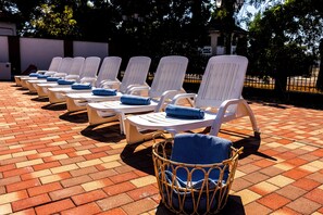 A row of white lounge chairs with blue towels, arranged on a brick patio. - Villa Oliver Abádszalók (Abádszalók)