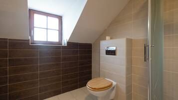 A bathroom with a wooden toilet, a window, and a shower area.