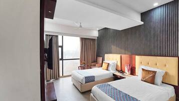 A hotel room with two beds, a large window, a flat-screen TV, and a wall-mounted panel.