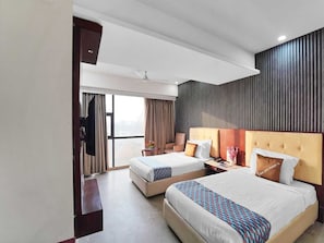 A hotel room with two beds, a large window, a flat-screen TV, and a wall-mounted panel. - Deluxe Twin Clubhouse Vytilla Kochi (Kanayannur)
