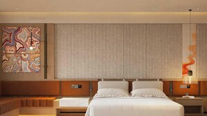 A modern hotel room with a large bed, a seating area, a decorative wall, and a unique light fixture. - Deluxe Twin Clubhouse Vytilla Kochi (Kanayannur)