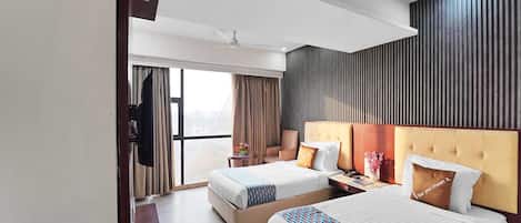 A hotel room with two beds, a flat-screen TV, a ceiling fan, and a large window with curtains.