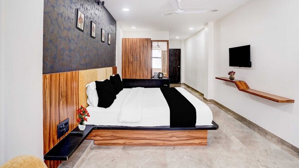 A modern bedroom with a wooden headboard, a flat-screen TV, a bedside table, and a nightstand. - Deluxe Twin Clubhouse Vytilla Kochi (Kanayannur)