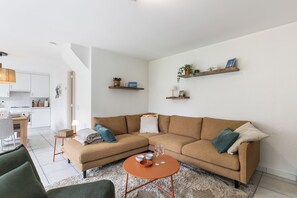 A living room with a sofa, coffee table, and kitchen in the background.