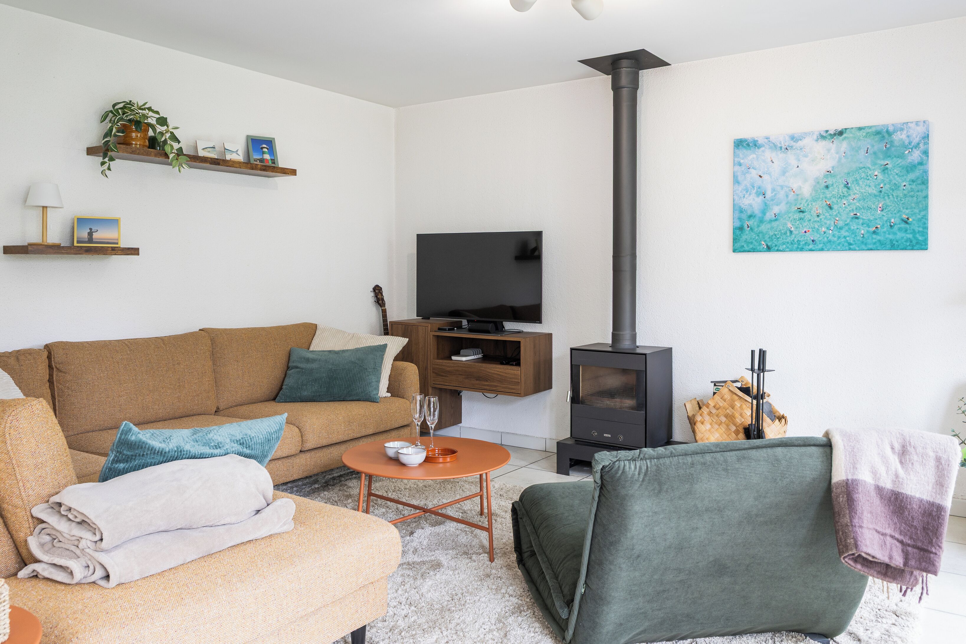 Una sala de estar con sofá, mesa de centro, televisor, chimenea y un cuadro en la pared.