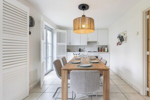 A dining area with a wooden table, chairs, and a hanging light fixture.
