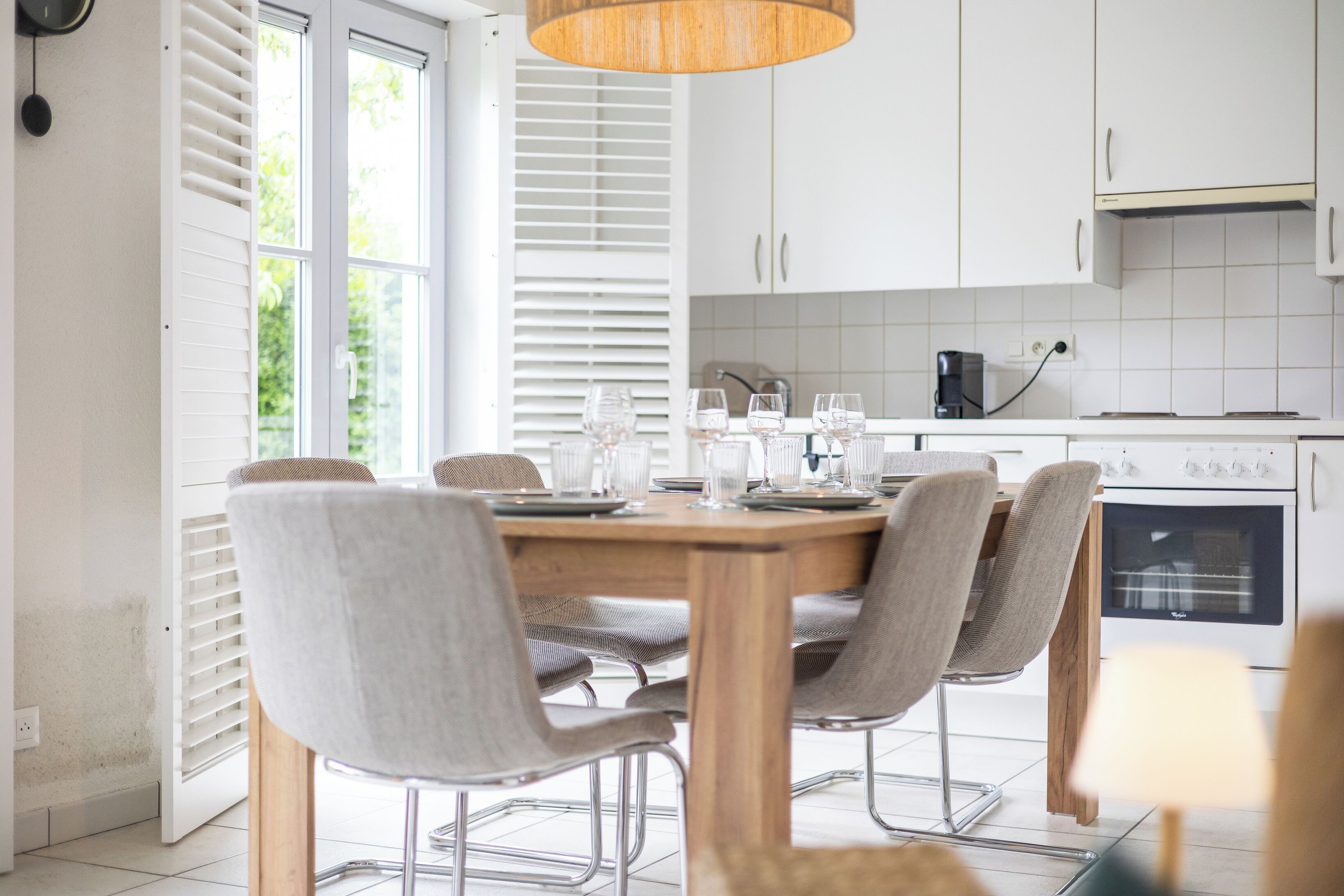 A modern kitchen with white cabinets, a wooden dining table, and four chairs.