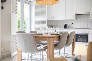 A modern kitchen with white cabinets, a wooden dining table, and four chairs. - Sea Side Village 91* (De Haan)