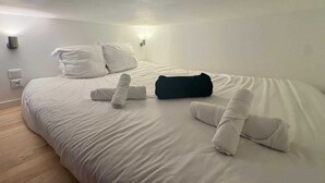 Une chambre d’hôtel avec un lit bien fait, une lampe fixée au mur et une prise de courant.