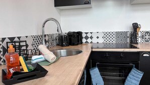 Une cuisine équipée d’un évier, d’une cuisinière, d’un four et de divers ustensiles de cuisine.