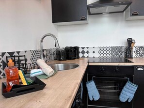 A kitchen with a sink, stove, oven, and various kitchen items. - Duplex lumineux centre-ville, tout équipé, parking (Le Mans)
