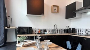 Une cuisine moderne équipée d’un four à micro-ondes, d’une cuisinière, d’un évier et de meubles de rangement noirs.