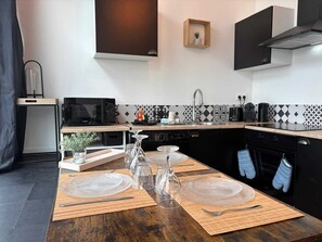 A modern kitchen with a microwave, stove, sink, and black cabinets. - Duplex lumineux centre-ville, tout équipé, parking (Le Mans)
