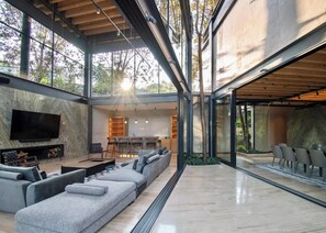 A modern interior with a large sofa, a flat-screen TV, and a dining area.