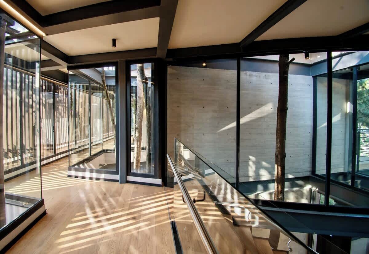 A modern interior with a glass railing, wooden flooring, and a view of the outdoors.