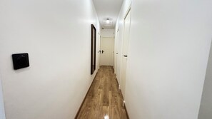 A narrow hallway with white walls, a wooden floor, and a door at the end. - Villa César - Private padel court, heated pool from March through November. (Bransles)