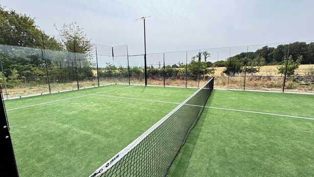 A tennis court with a net, surrounded by a fence and trees. - Villa César - Private padel court, heated pool from March through November. (Bransles)