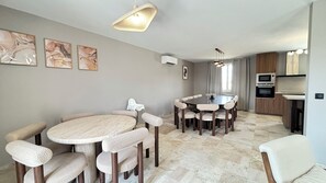 A modern dining area with a round table and chairs, a kitchen with built-in appliances, and a ceiling light fixture. - Villa César - Private padel court, heated pool from March through November. (Bransles)
