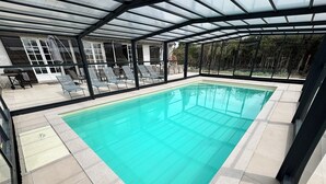A swimming pool with a glass enclosure, lounge chairs, and a view of the surrounding area. - Villa César - Private padel court, heated pool from March through November. (Bransles)