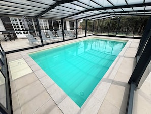 A swimming pool with a glass enclosure, lounge chairs, and a view of the surrounding area. - Villa César - Private padel court, heated pool from March through November. (Bransles)