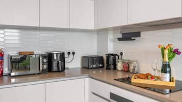 A modern kitchen with a microwave, coffee maker, toaster, and a vase with flowers on the counter.