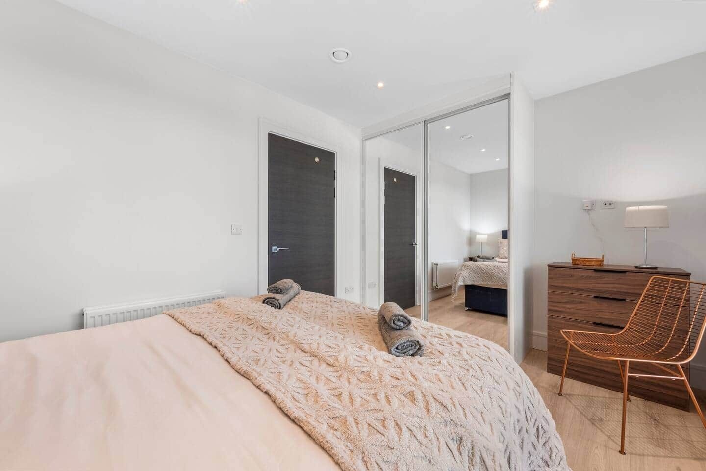 A bedroom with a bed, a dresser, a chair, and a door leading to another room.