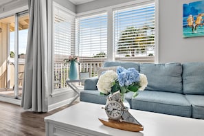 A living room with a grey sofa, a white coffee table, and a clock. - 🌴Sandpiper Cove 2015~ 5 Pools + 3 Hot Tubs~ Tennis Courts + Golf Course ⛳ (Destin)