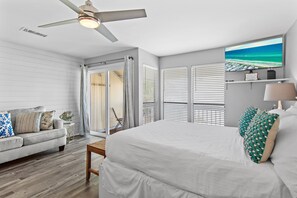 Une chambre à coucher comprenant un lit, un ventilateur de plafond, une fenêtre avec vue, un canapé et une petite table.