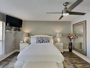 A bedroom with a bed, nightstands, a TV, a ceiling fan, a mirror, and a window with blinds. - 🌴Sandpiper Cove 8246~Steps2beach- 5 Pools~3 Hot Tubs~Tennis Courts~Golf Course⛳ (Destin)