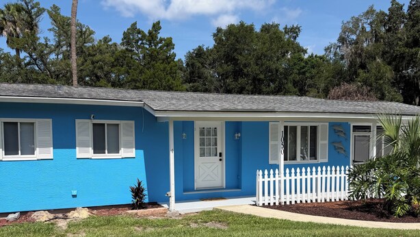 A single-story house with a blue exterior, white shutters, and a white picket fence. - Perfect 3-bedroom2-bath house in the heart of Crystal River. (Crystal River)