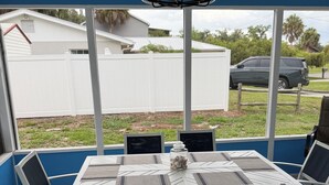 An outdoor patio with a table and chairs, a ceiling fan, and a view of a white fence and parked car. - Perfect 3-bedroom2-bath house in the heart of Crystal River. (Crystal River)