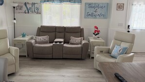A living room with a beige sofa, two side tables, a coffee table, and a window with blinds. - Perfect 3-bedroom2-bath house in the heart of Crystal River. (Crystal River)