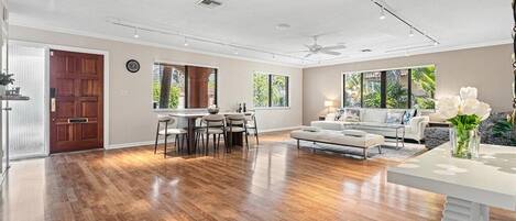 A spacious living area with hardwood flooring, a dining table, and a sofa.