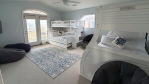 A bedroom with bunk beds, a ceiling fan, a window, and a door. - Mischief Managed NC-  Marsh and Beach views!  Private Pool, Pet Friendly (Oak Island)