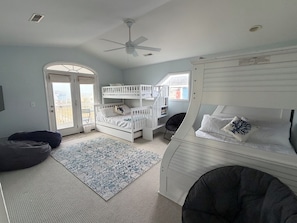 Ein Schlafzimmer mit Etagenbetten, Deckenventilator, Fenster und Tür.