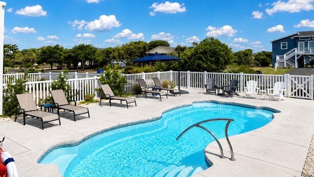 A swimming pool with lounge chairs and a white fence. - Mischief Managed NC-  Marsh and Beach views!  Private Pool, Pet Friendly (Oak Island)