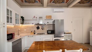 Eine Küche mit weißen Schränken, einem Holztisch und einem Edelstahlkühlschrank.