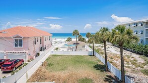 Ein Anwesen direkt am Strand mit Pool, ein rotes Auto auf der Auffahrt und Blick aufs Meer.