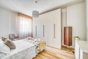 Un dormitorio moderno con cama, una silla, armario y lámpara de pie.