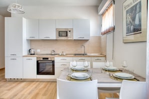 A modern kitchen with white cabinetry, a built-in microwave, and a dining area set for four with a marble table. - A cozy apartment of approximately 60 sqm, perfect for a stay for two, located on the third floor of a building with an elevator.The property is situated in Magione, Umbria, just minutes from Lake Trasimeno in a well-serviced area offering all key ameniti (Magione)