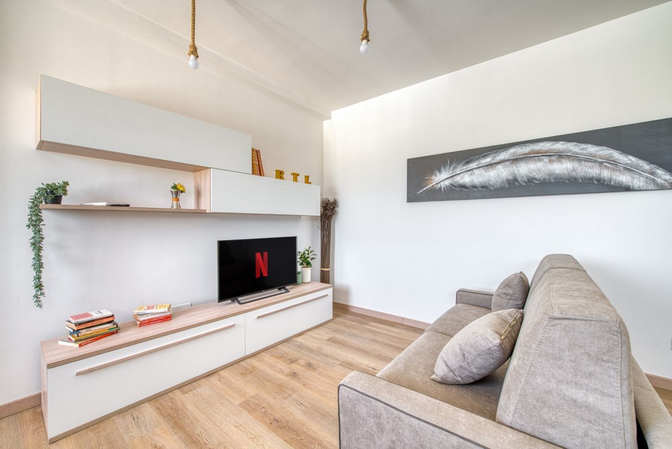 Una sala de estar moderna con un televisor de pantalla plana, un sofá y una obra de arte colgada en la pared.