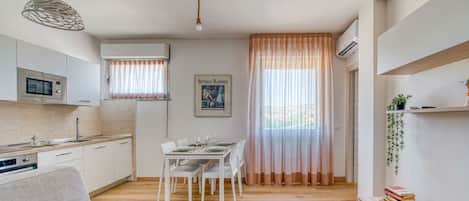A modern kitchen with white cabinets, a dining table set for four, and a hanging pendant light.