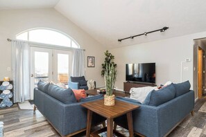 A living room with a sofa set, a coffee table, a TV, and a plant.