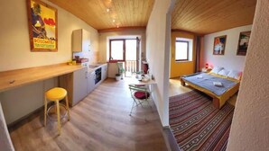 A room with a bed, a desk, and a chair. There is a window and a door.