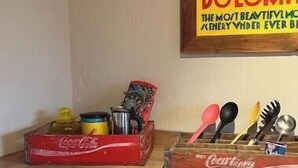 A wooden desk with a red Coca-Cola crate, a yellow stool, and a vintage poster.