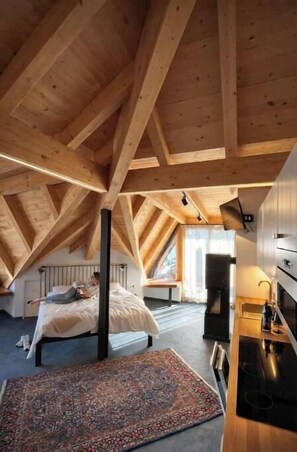 Ein Schlafzimmer mit schrägem Dach, einem Bett, einem Nachttisch und einem Fenster.