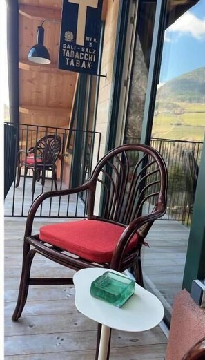 A wooden deck with a wicker chair and a small table. - To the Bahngarten 1907 – Historic train station building with a panoramic view (Bolzano)