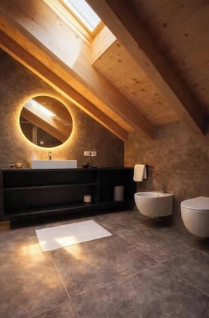 A modern bathroom with a skylight, a round mirror, a black vanity, and two sinks. - To the Bahngarten 1907 – Historic train station building with a panoramic view (Bolzano)