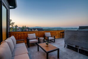 Une terrasse sur le toit équipée d’un canapé, de chaises, d’une table et d’un barbecue.
