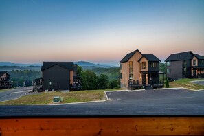 A residential area with modern houses, a paved road, and a view of distant hills. - Luxury Roof Top Cabin! Splashing Views! Pool! Hot Tub! Gaming Simulator! (Sevierville)